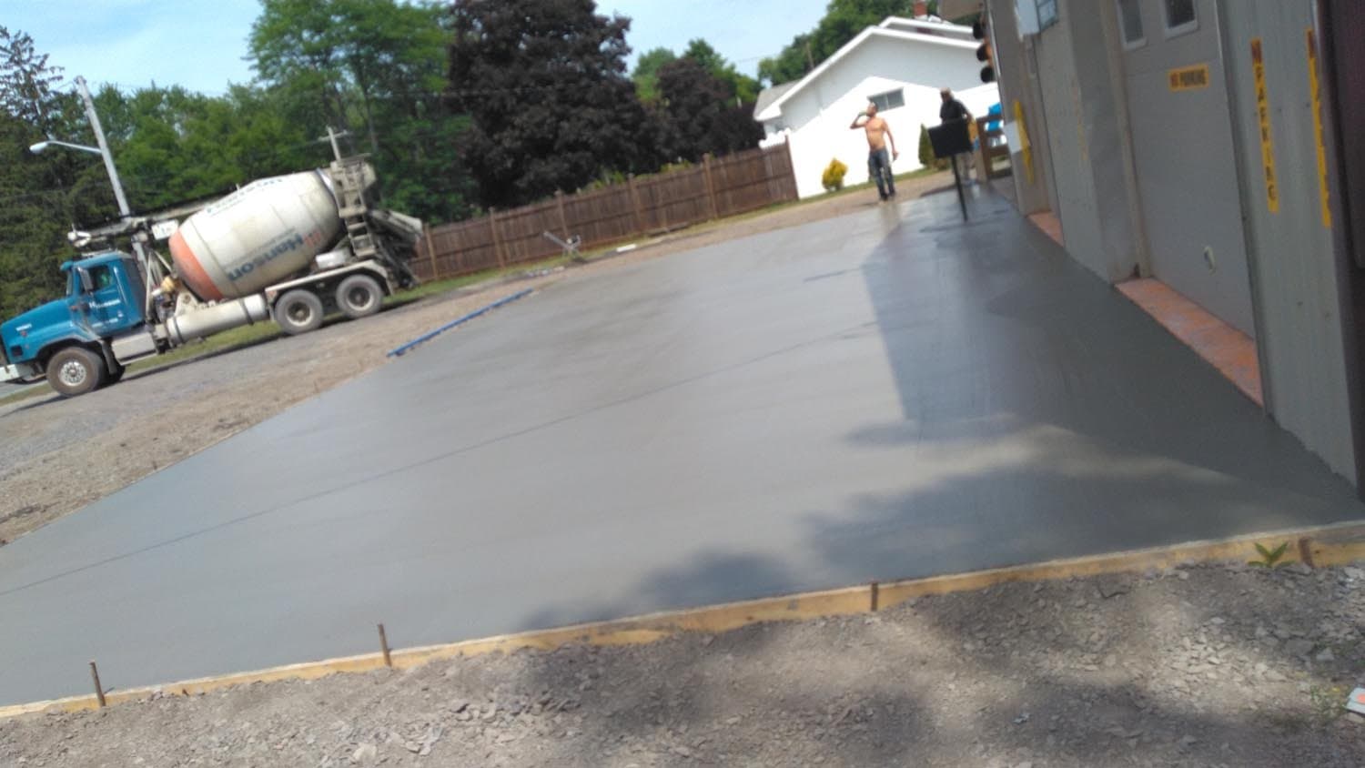 Fresh concrete driveway being poured next to cement mixer truck