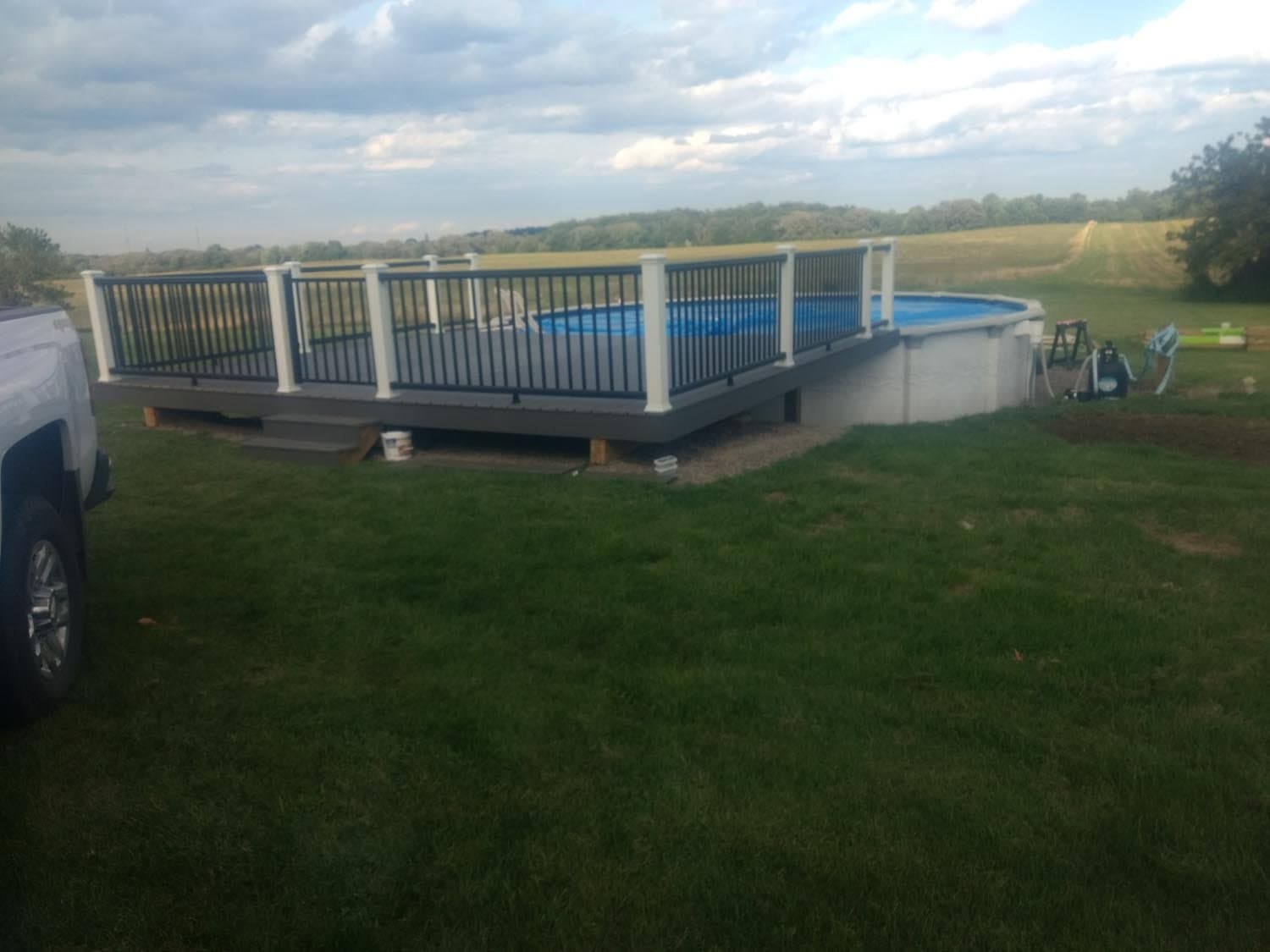 Above-ground pool with surrounding custom deck in rural backyard
