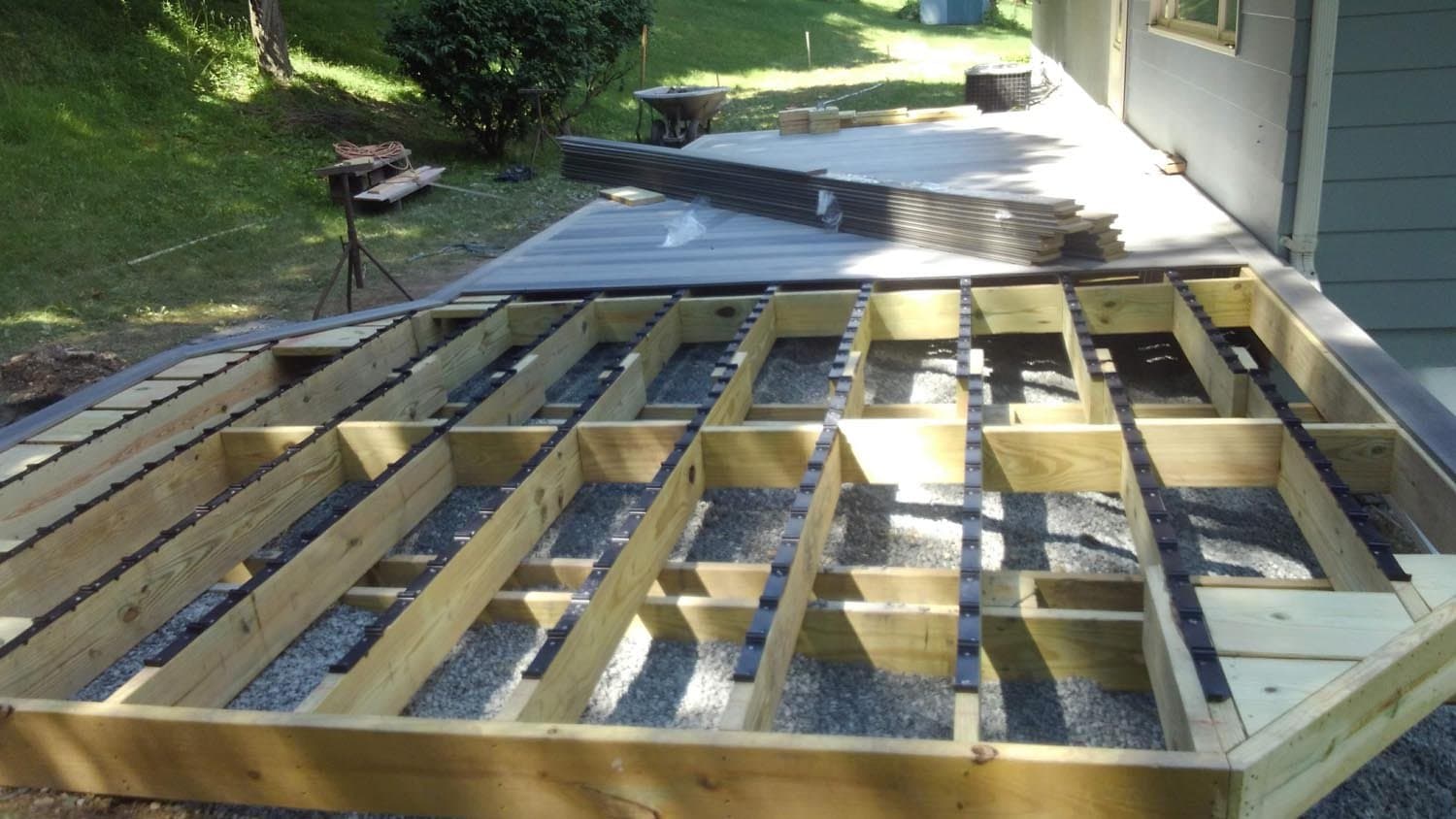 Wooden deck frame with joists and black support strips during construction