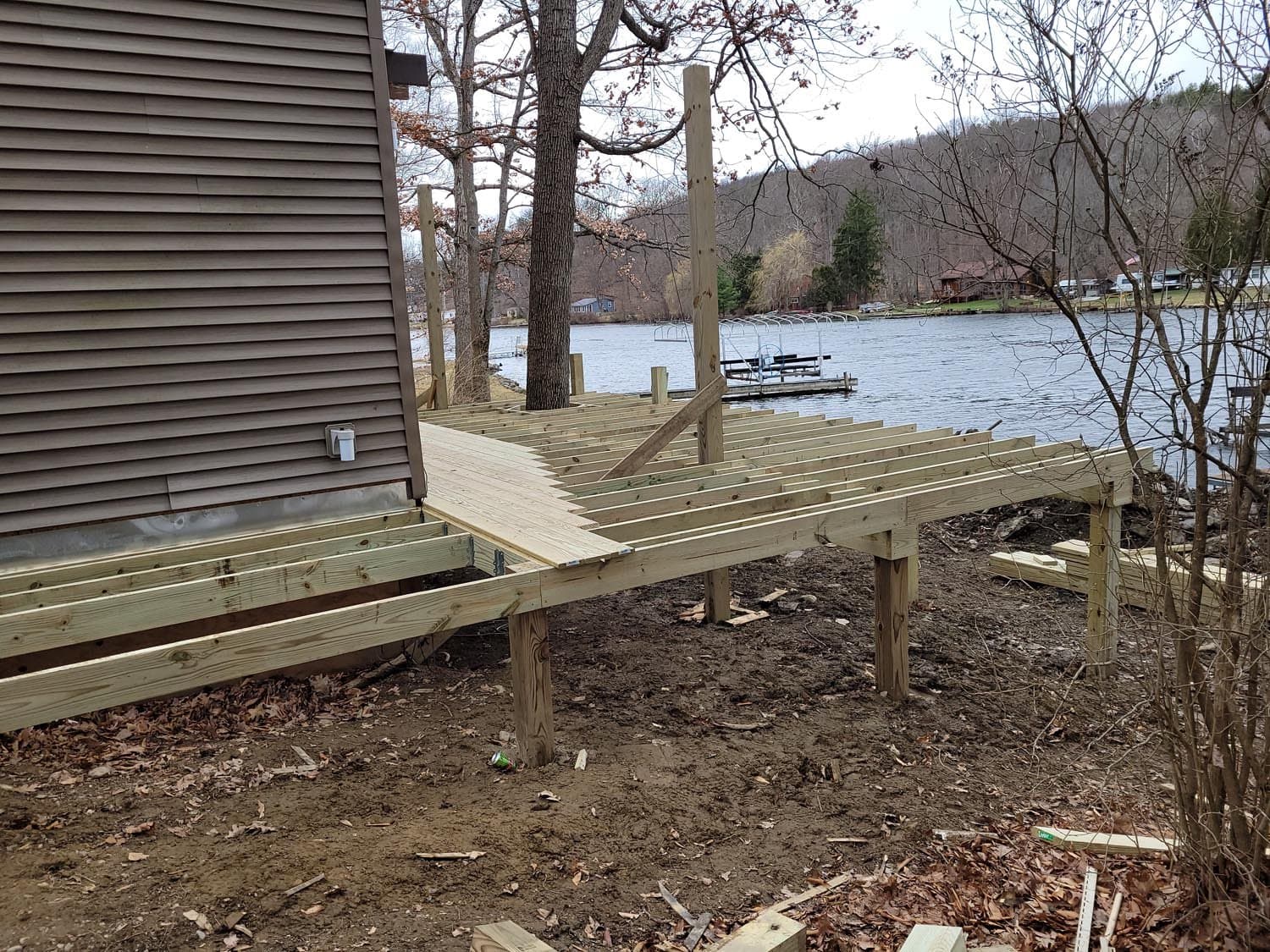 Wooden deck frame under construction beside lakefront house