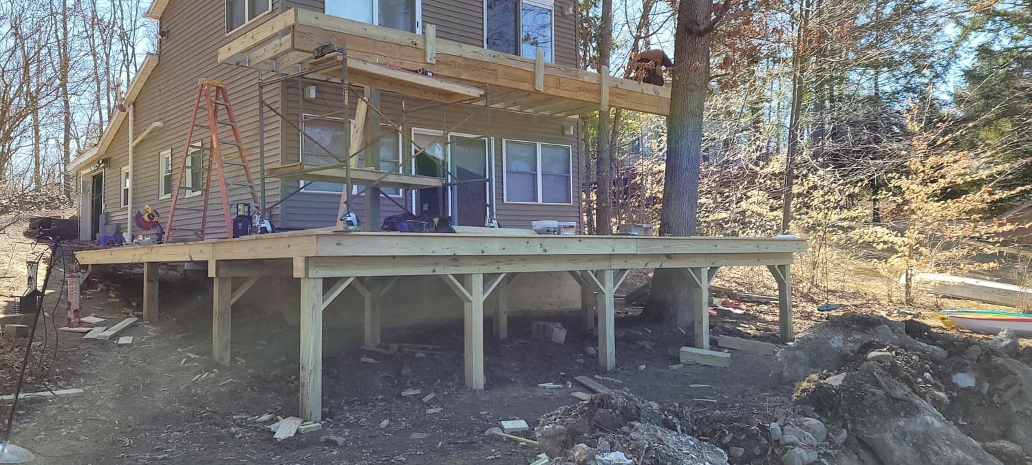 Two-story house with elevated deck under construction on wooden support posts