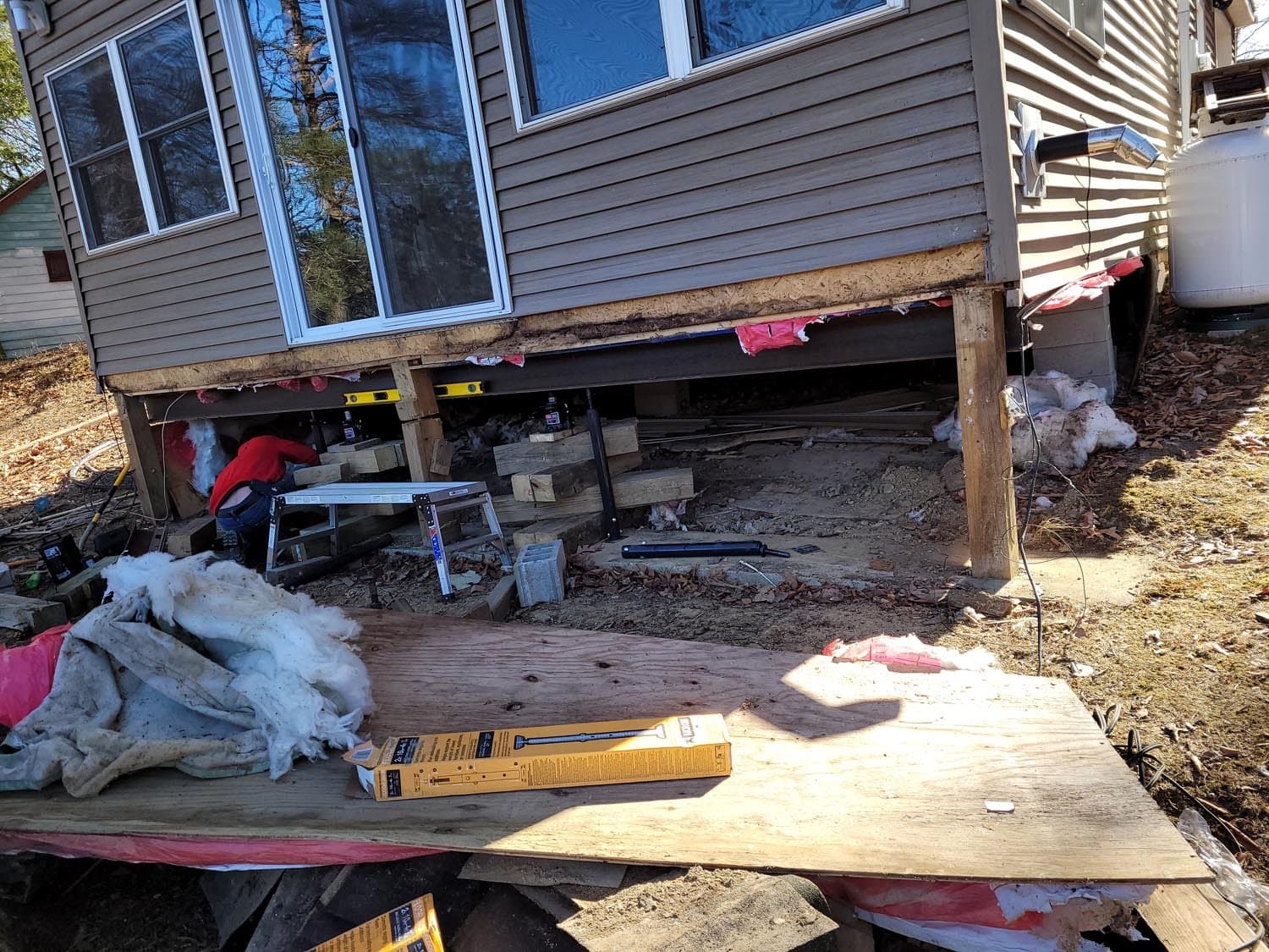 House elevated on supports during foundation repair work with exposed crawl space