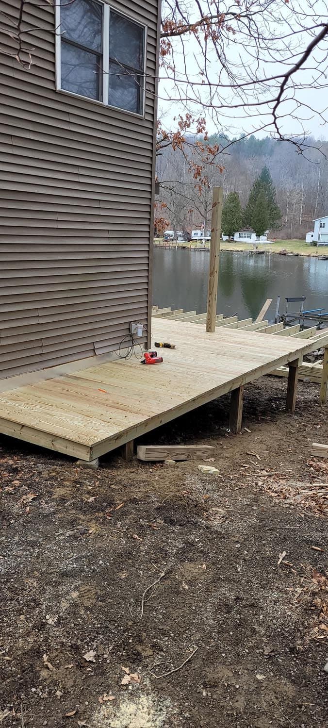 New wooden deck under construction extending toward lake with boat dock