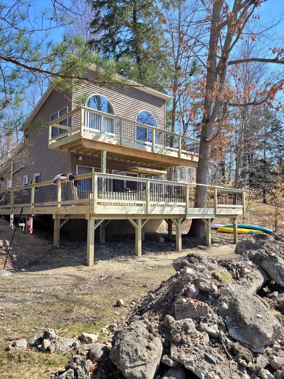 Two-story custom deck on waterfront home with arched windows and kayak storage