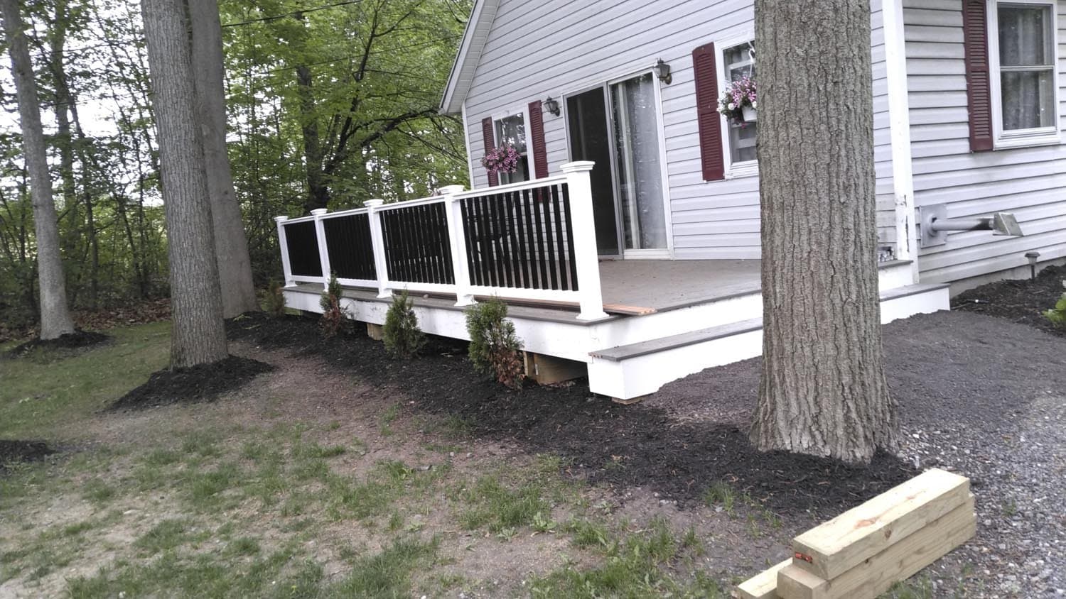 White deck with black railing and steps surrounded by trees