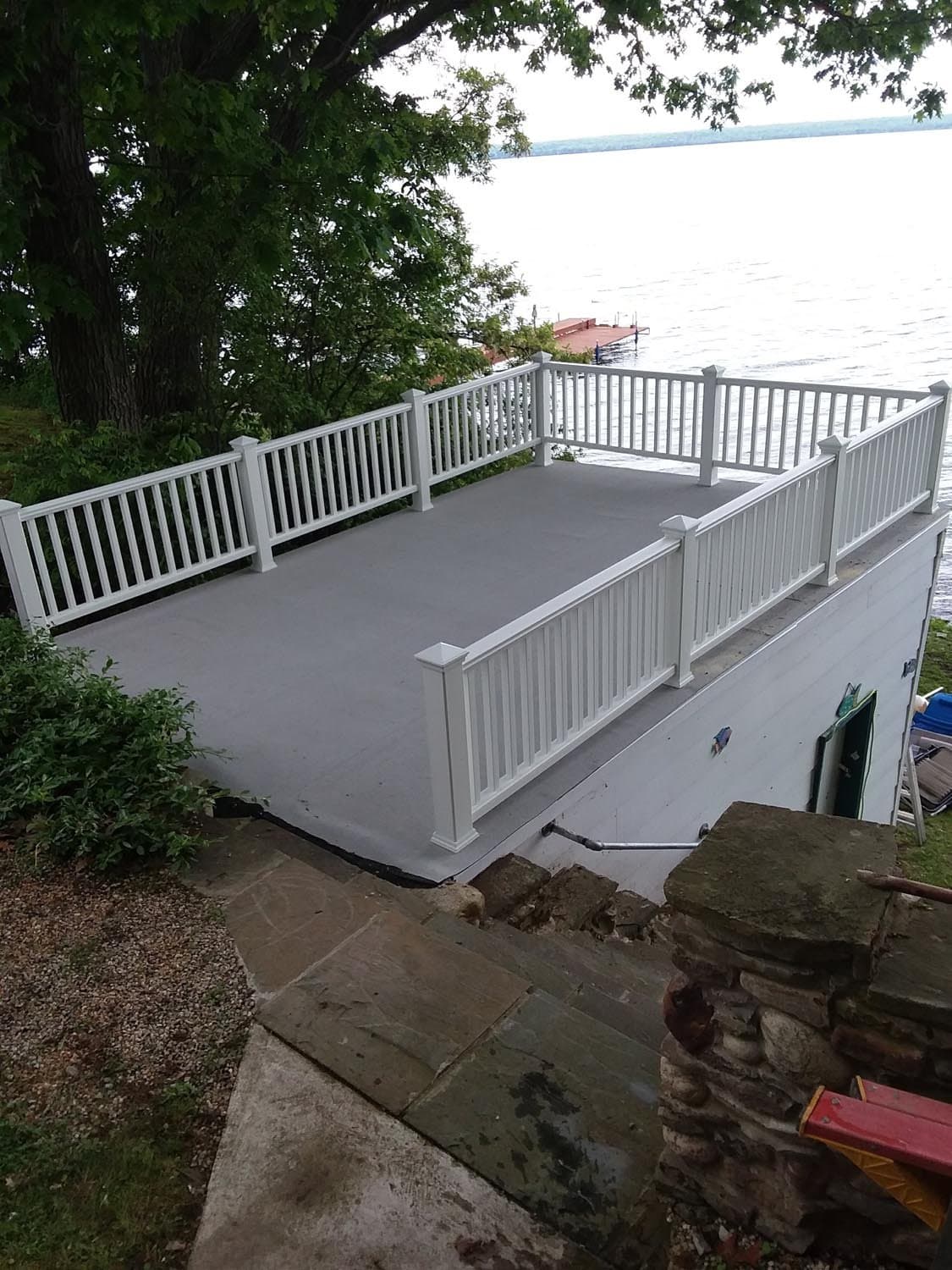 White composite deck with vertical railings overlooking a lake with dock