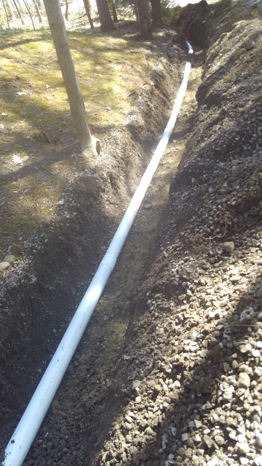 White PVC drainage pipe laid in excavated trench with gravel
