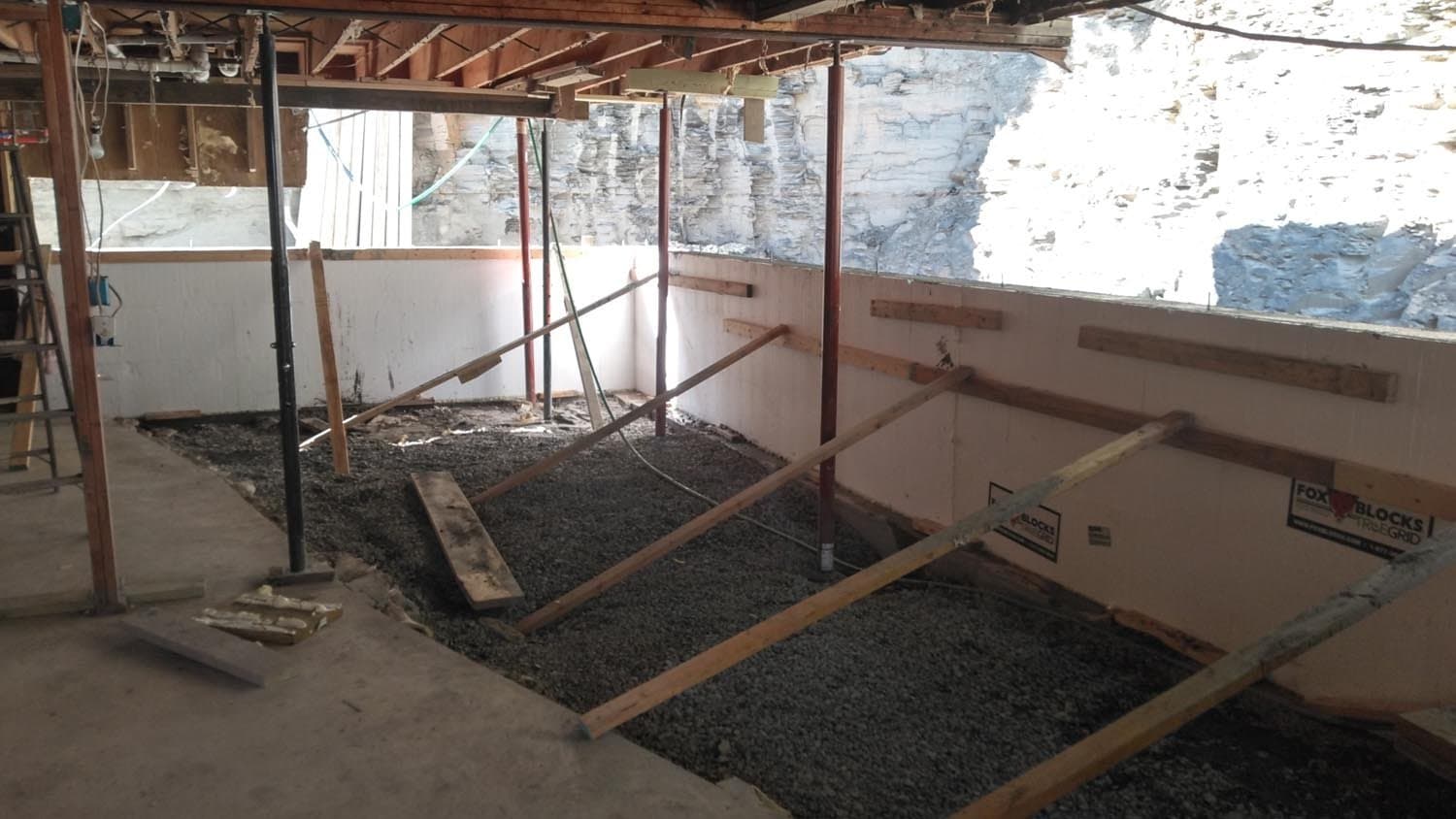 Basement foundation preparation with gravel fill and wooden framing supports