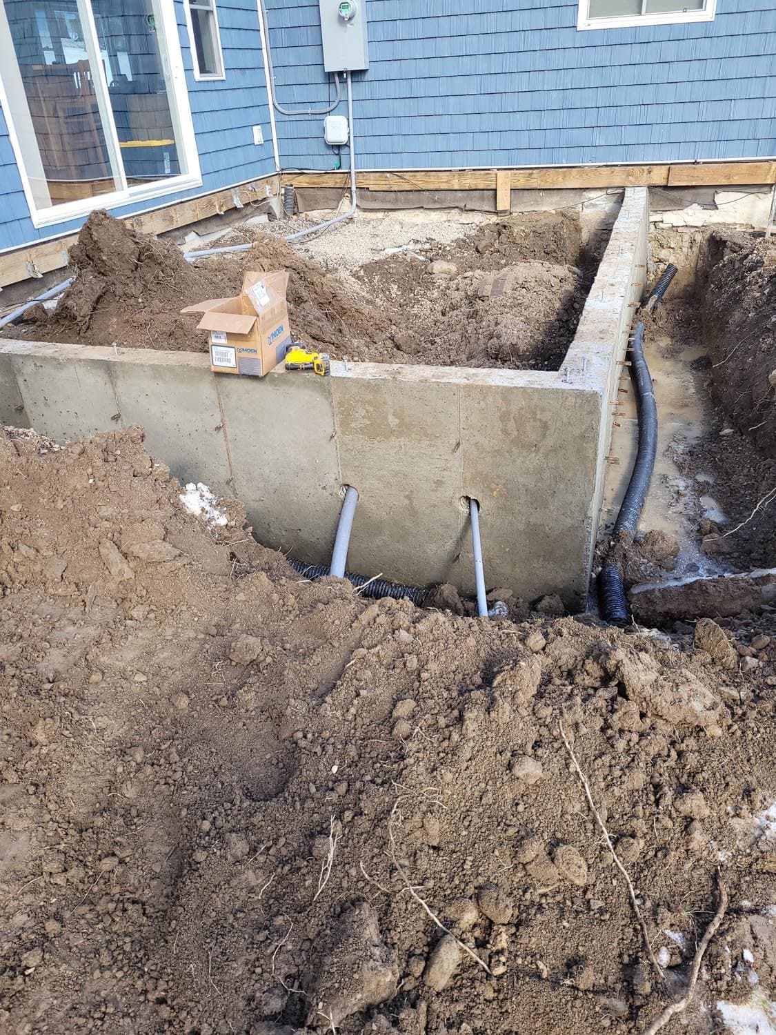 Concrete foundation walls with plumbing pipes during excavation at residential construction site