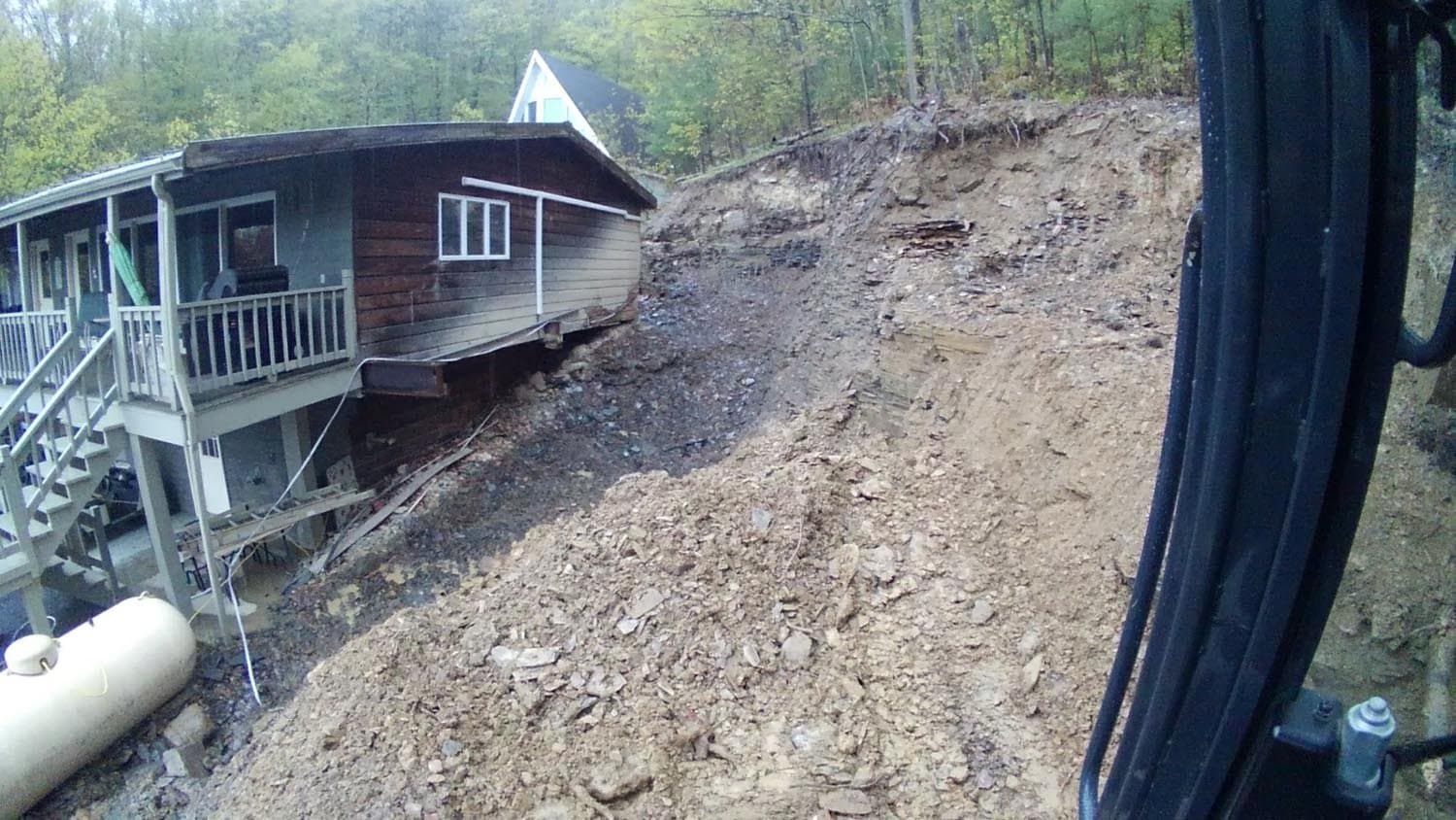 Excavated hillside next to cabin showing prepared foundation site and exposed earth