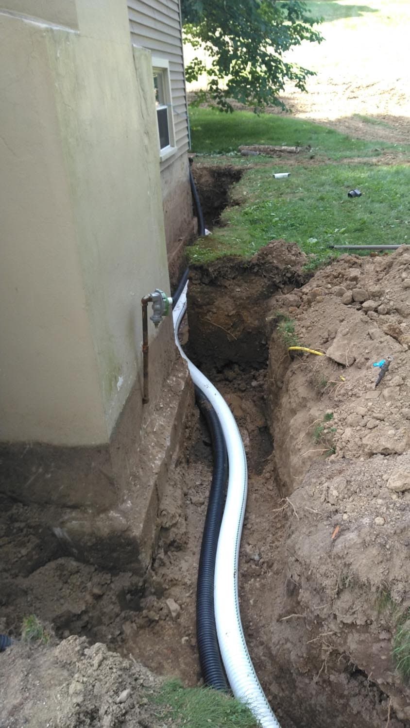 Corrugated drainage pipe installed in trench along house foundation