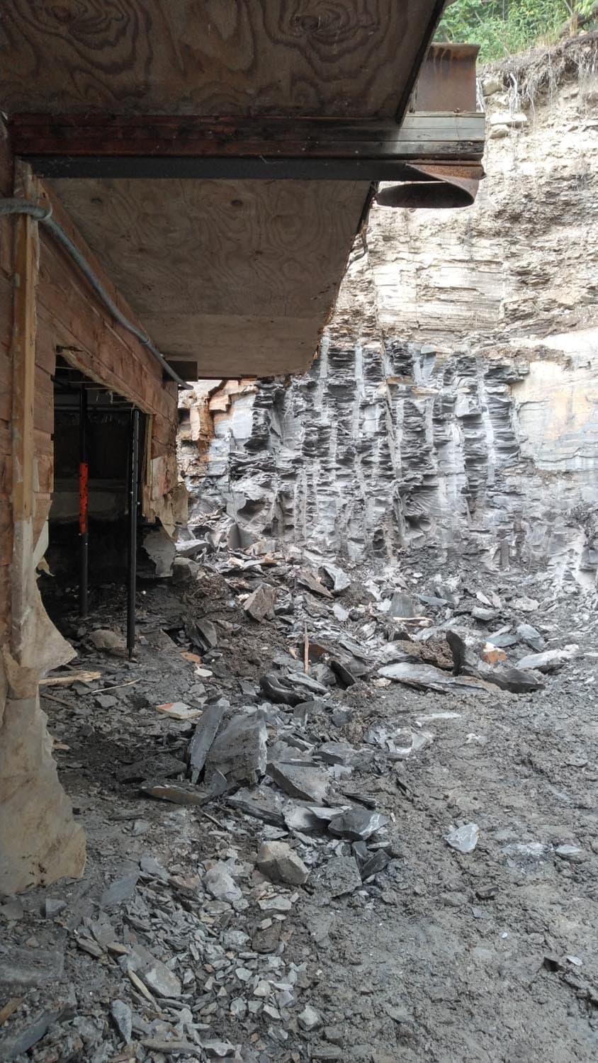 Excavated foundation wall during construction showing exposed concrete and debris