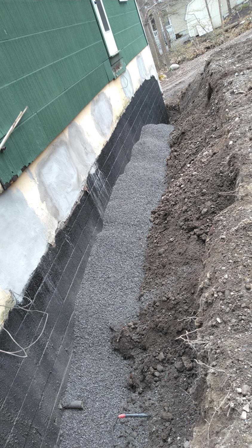 Foundation wall with black waterproofing membrane and gravel drainage system