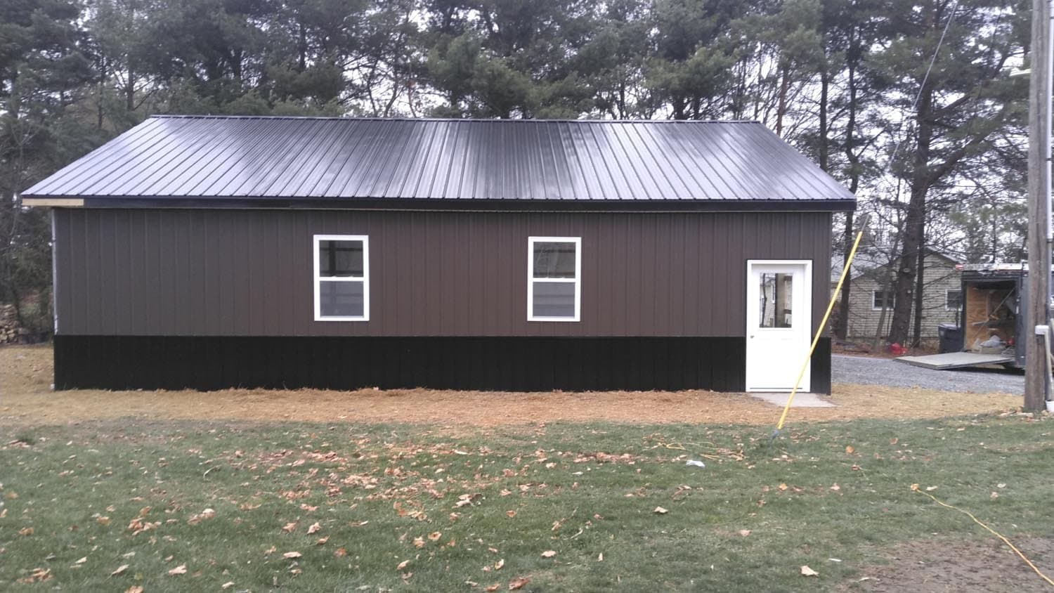 Brown pole barn with metal roof and white trim windows and door
