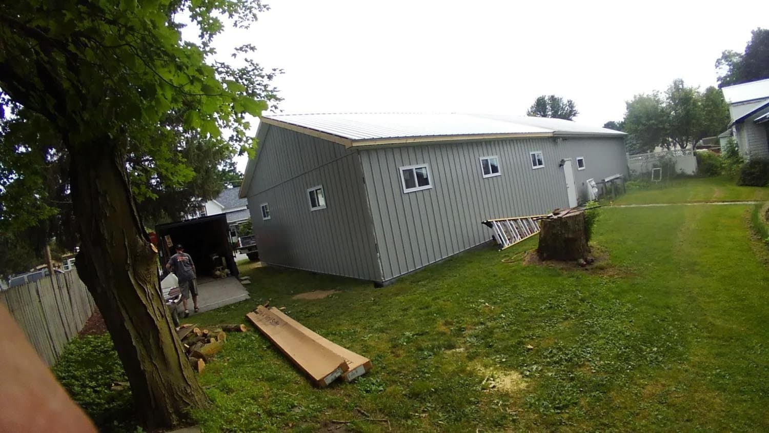 Gray pole barn severely collapsed and tilted to one side in residential yard