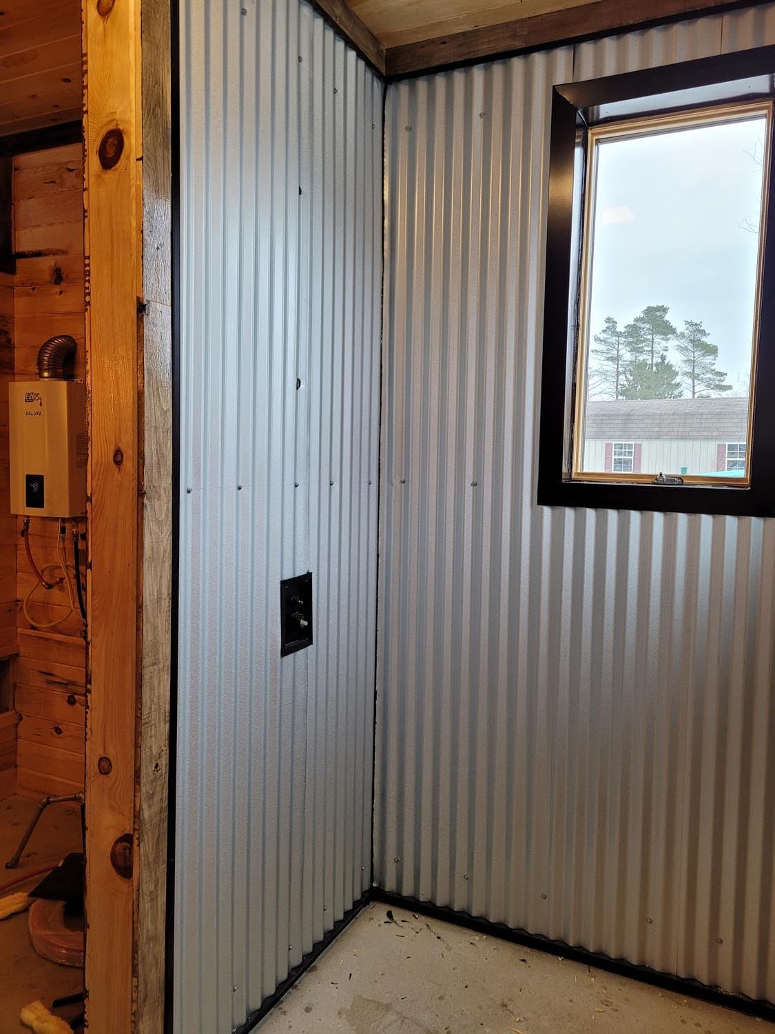 Interior corner of pole barn with corrugated metal walls and black-framed window