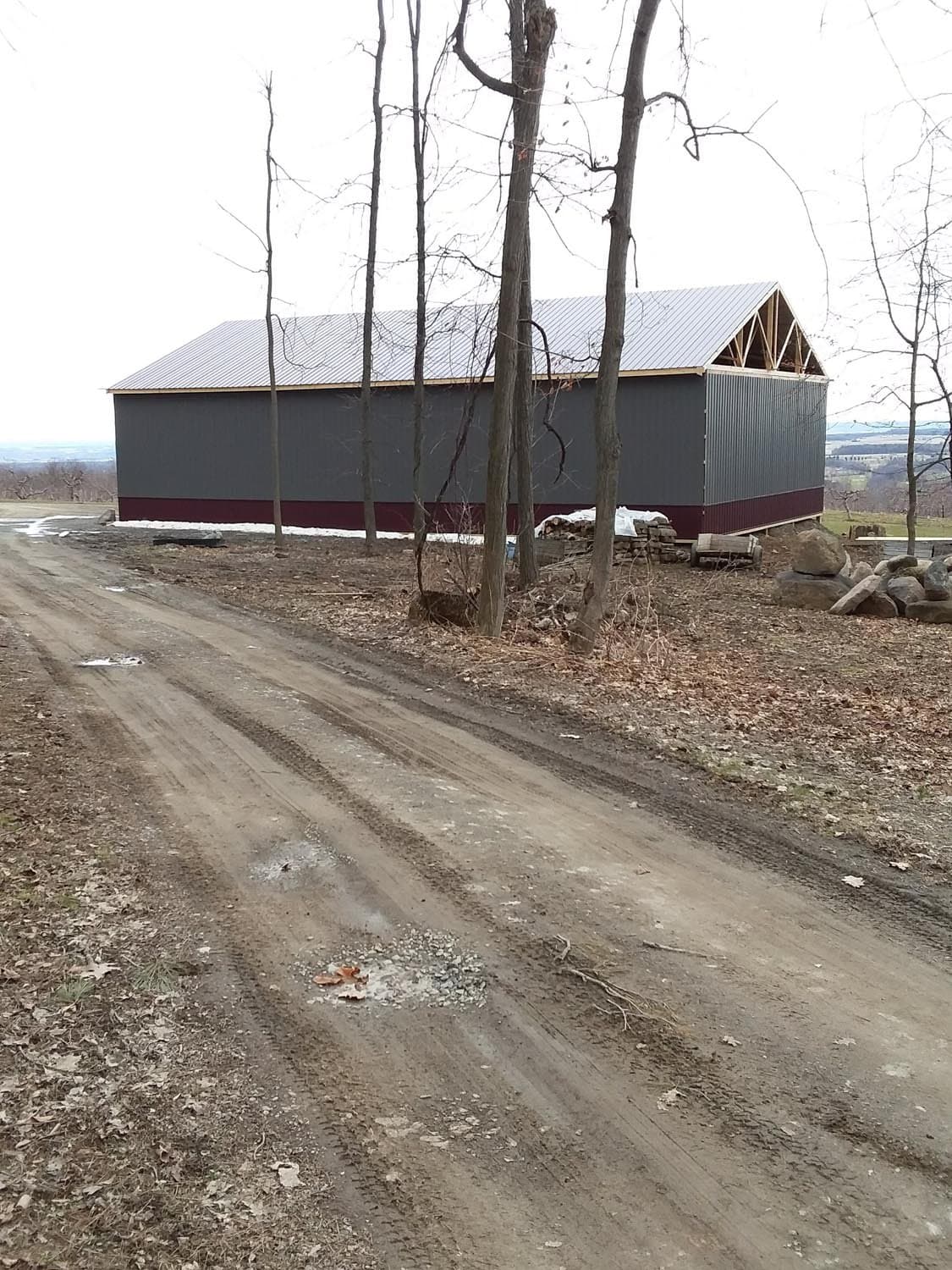 Newly constructed gray and red pole barn with metal roof on rural property