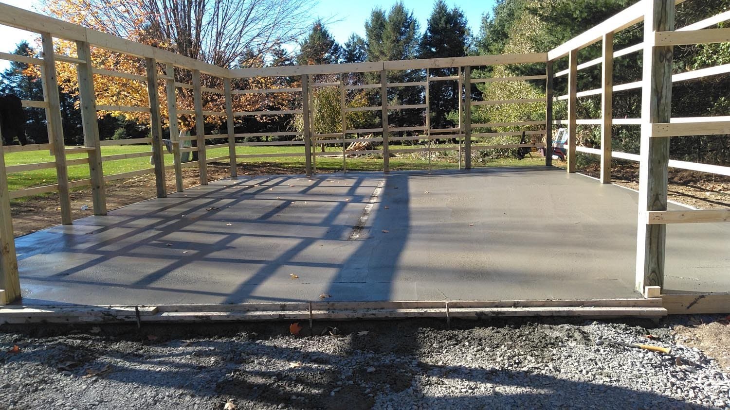 Concrete slab foundation with wooden post-frame structure for pole barn under construction