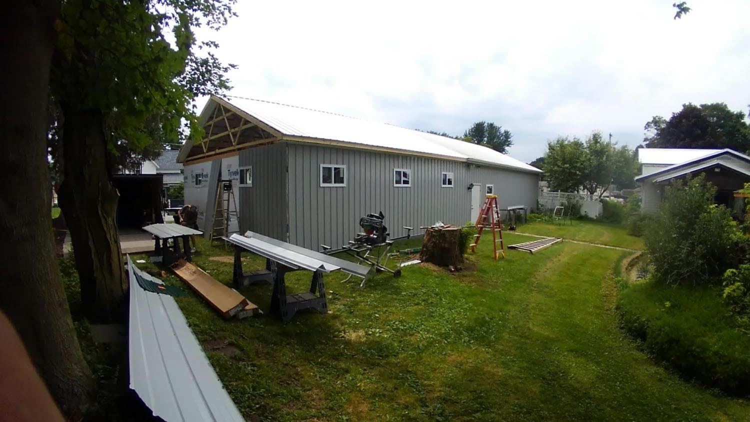 Gray pole barn under construction with exposed roof trusses and metal siding