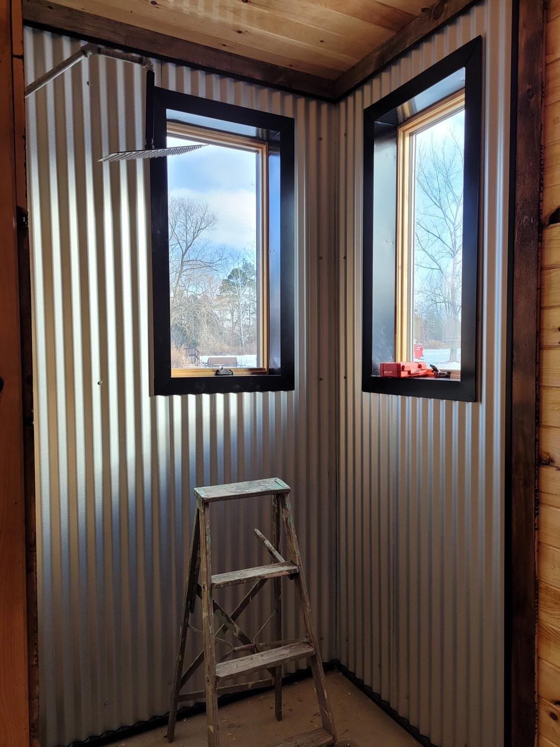 Corner windows with black frames in corrugated metal pole barn interior