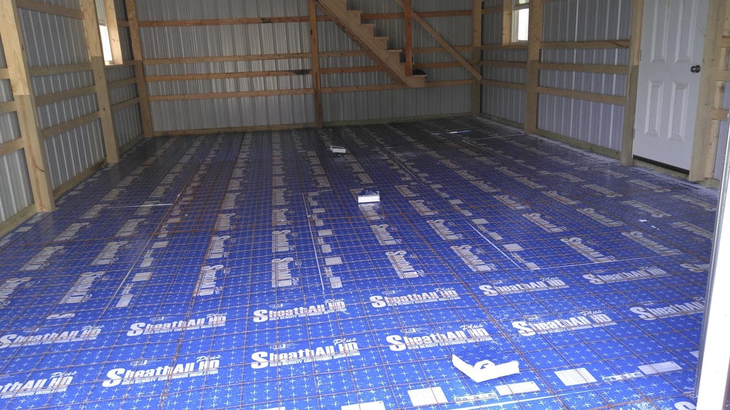 Blue SheathAll HD insulation installed on pole barn floor with exposed wooden framing