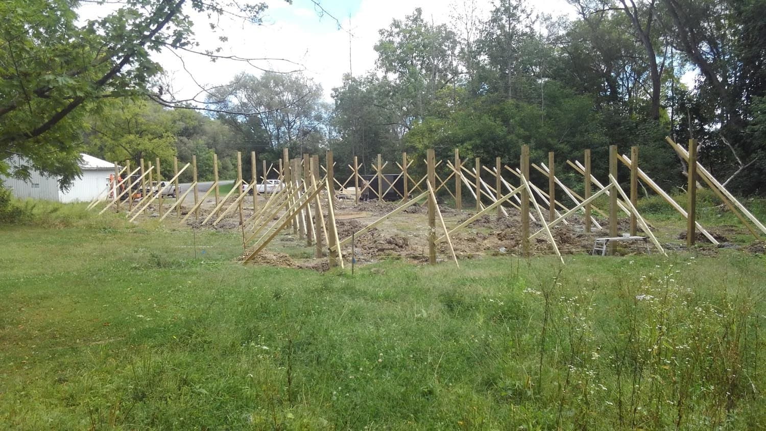Wooden support posts and bracing for pole barn foundation in grassy field