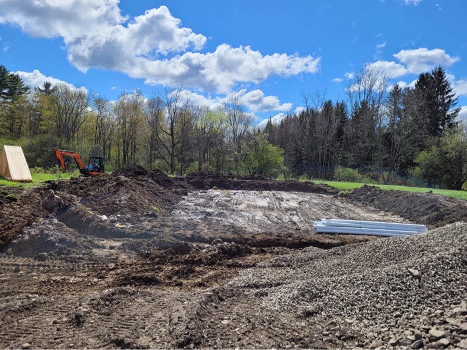Excavated foundation site for pole barn construction with equipment and materials