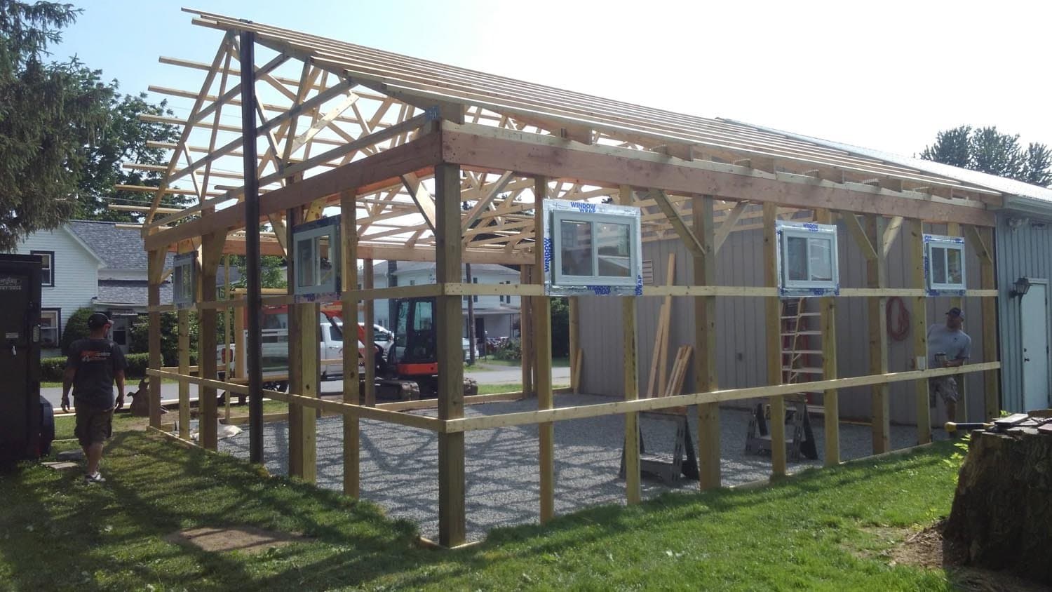 Wooden pole barn frame under construction with exposed roof trusses and windows