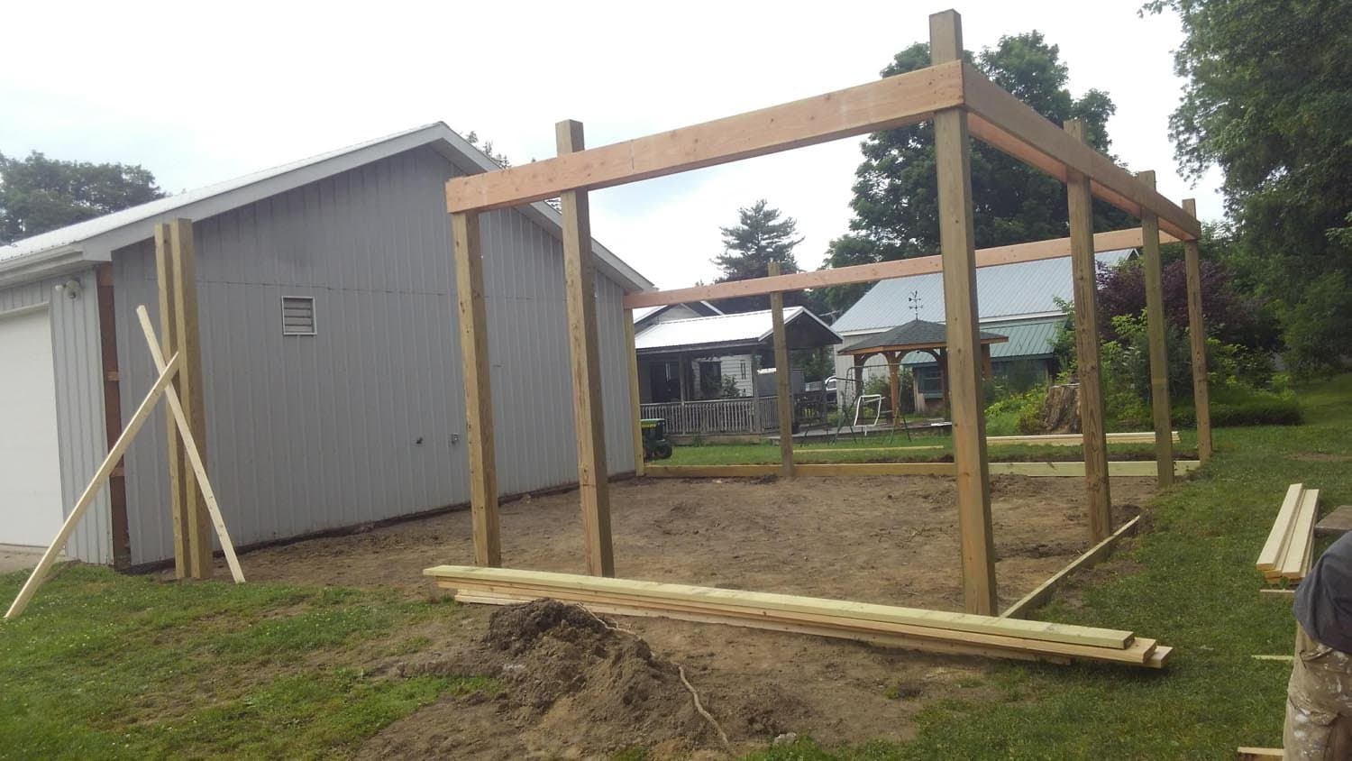Wooden frame structure for pole barn under construction in residential backyard