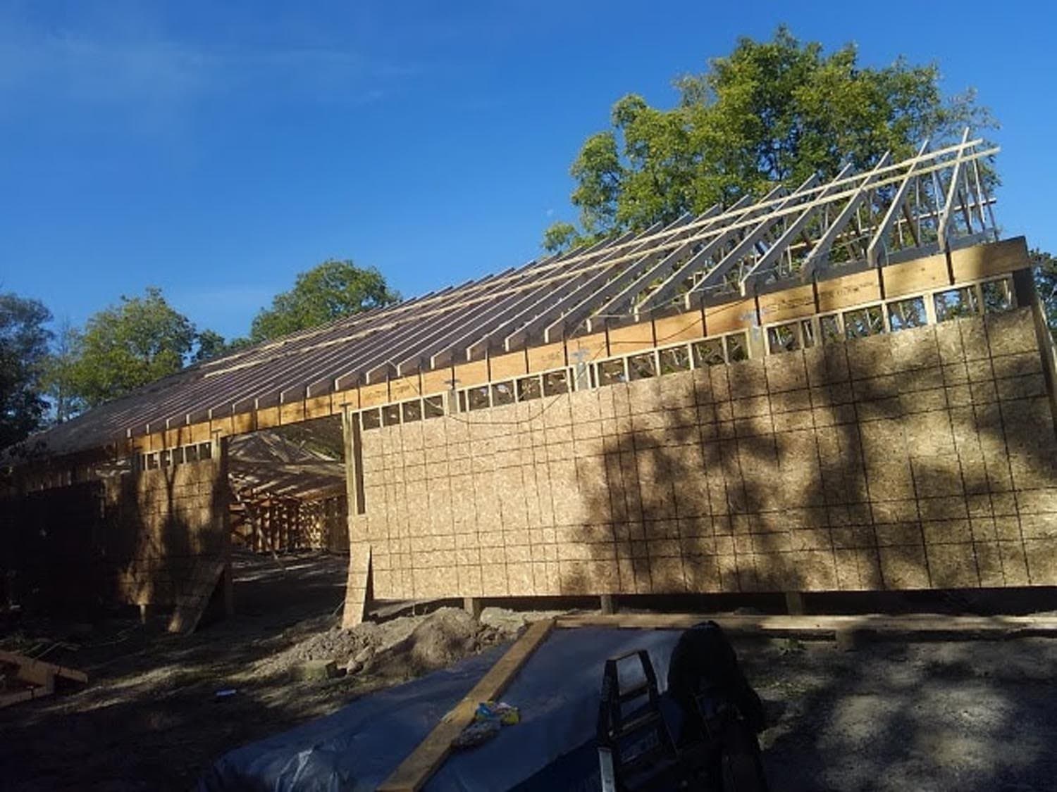 Pole barn under construction with timber frame and exposed wood walls