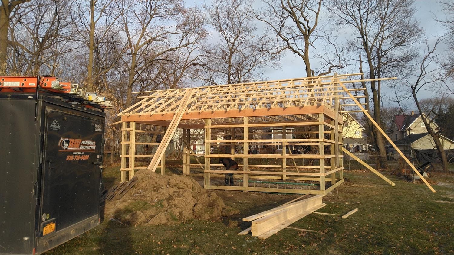 Wooden frame structure of pole barn under construction with roof trusses