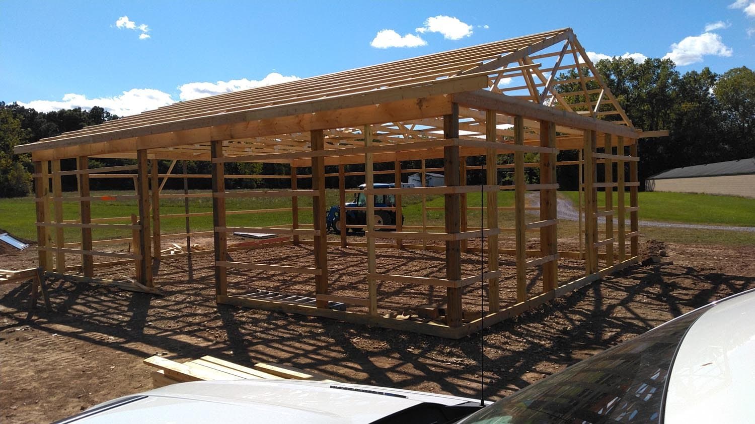 Wooden pole barn frame under construction with exposed roof trusses