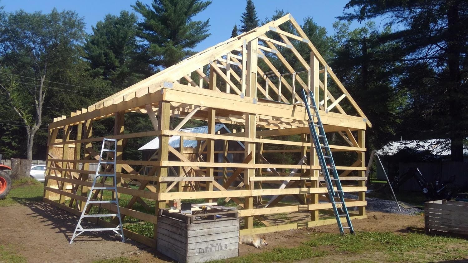 Wooden pole barn frame under construction with exposed rafters and trusses