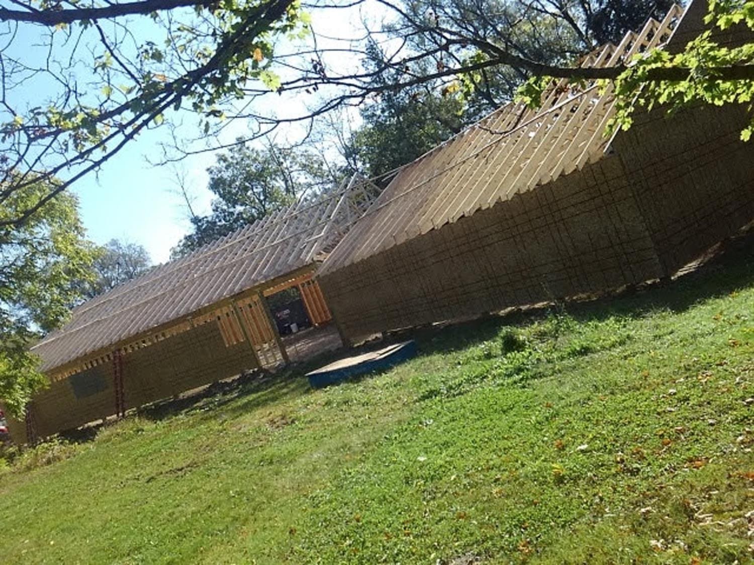 Newly constructed pole barn with steep roof on grassy hillside