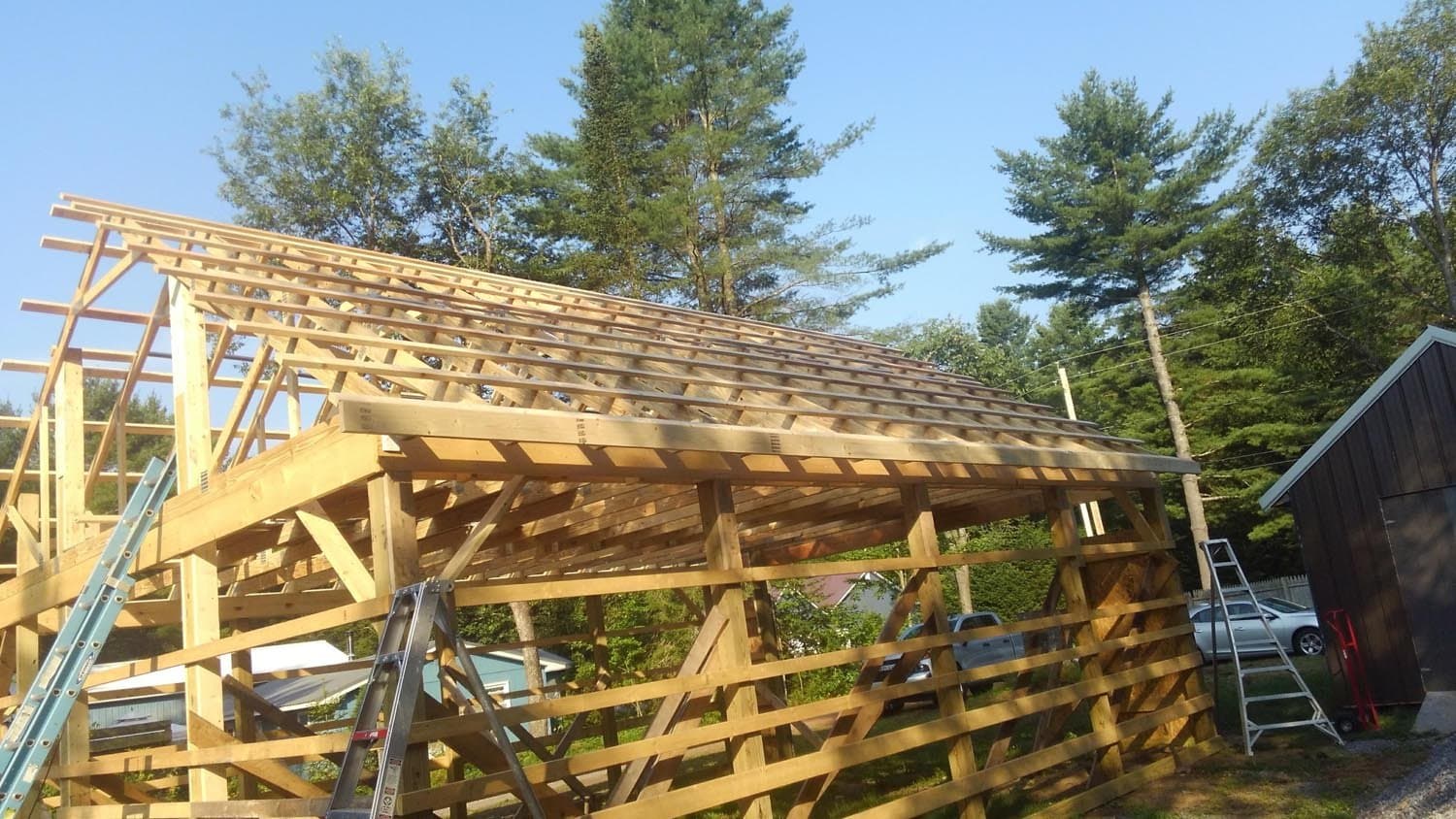 Timber frame pole barn under construction showing exposed roof trusses and rafters