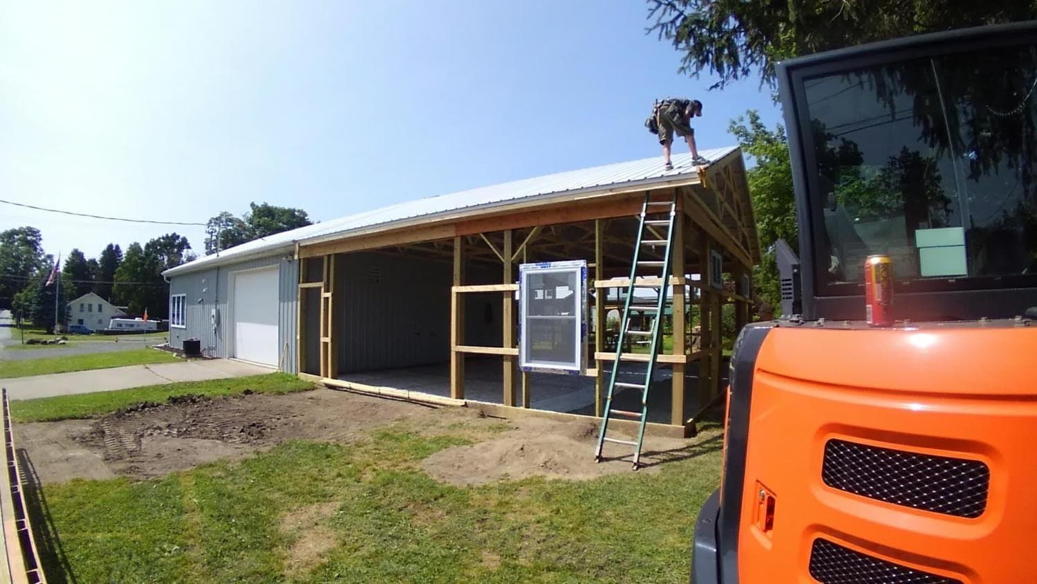 Worker installing metal roofing on custom pole barn under construction