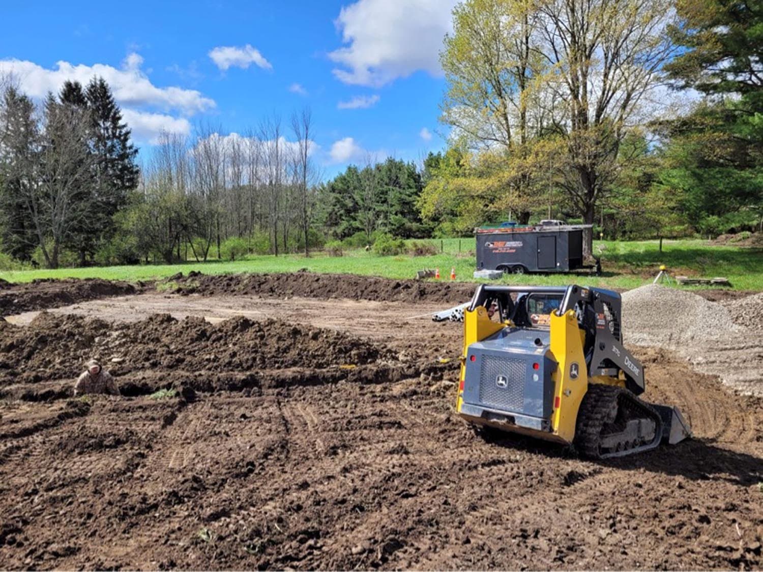 Yellow track skid steer grading excavated ground for pole barn foundation