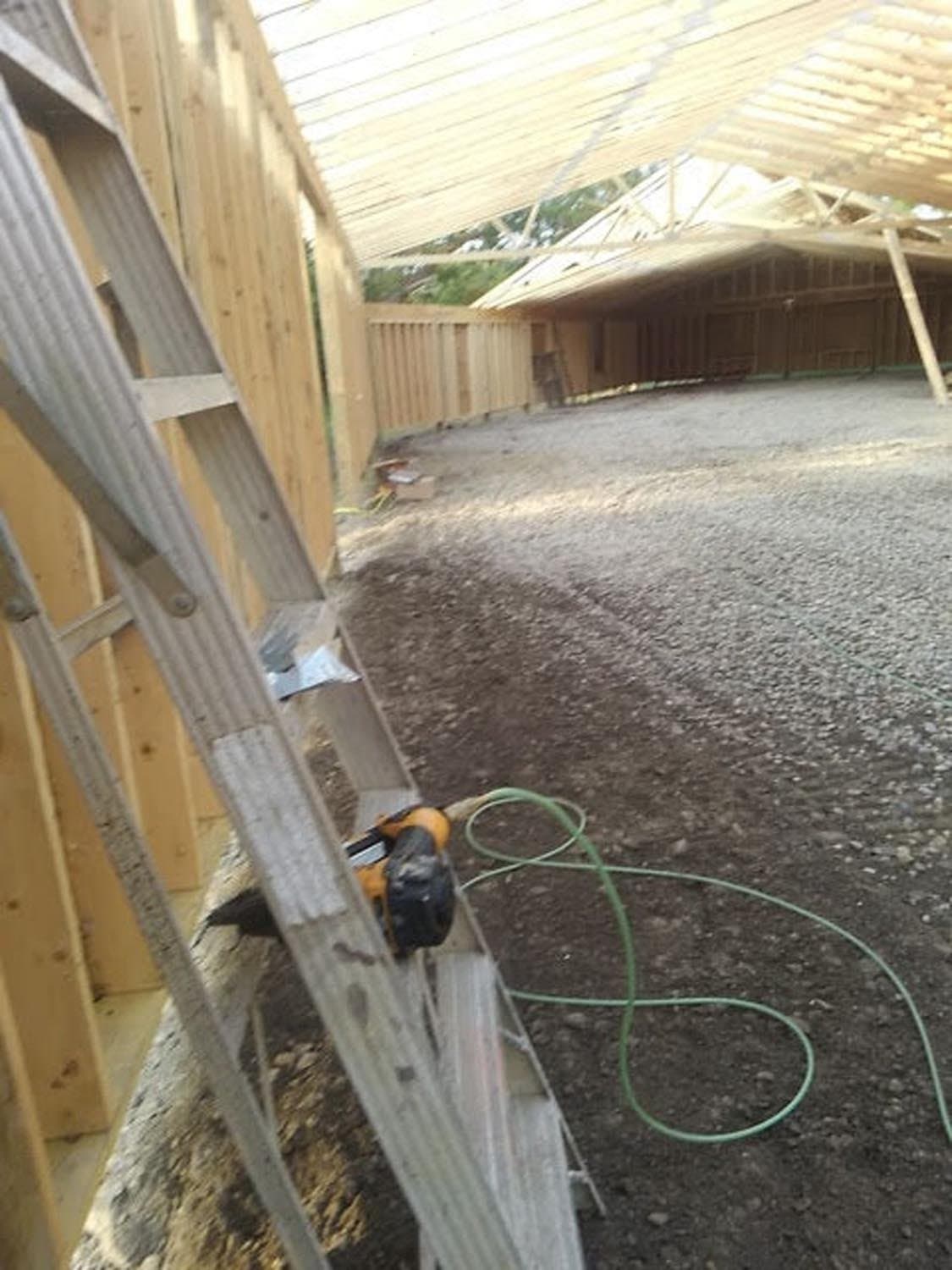 Pole barn construction site showing wooden frame structure and gravel foundation