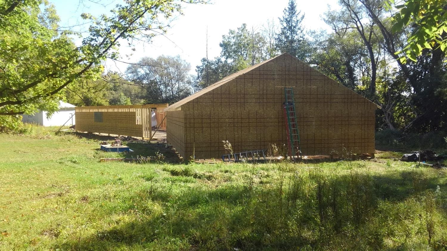Wood-framed pole barn under construction with ladder leaning against gabled side