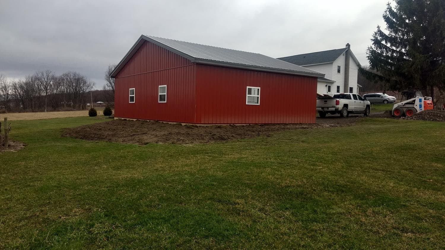 Red pole barn with metal roof and windows on residential property