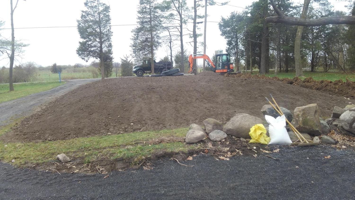 Excavation site with orange excavator and exposed soil for septic system installation