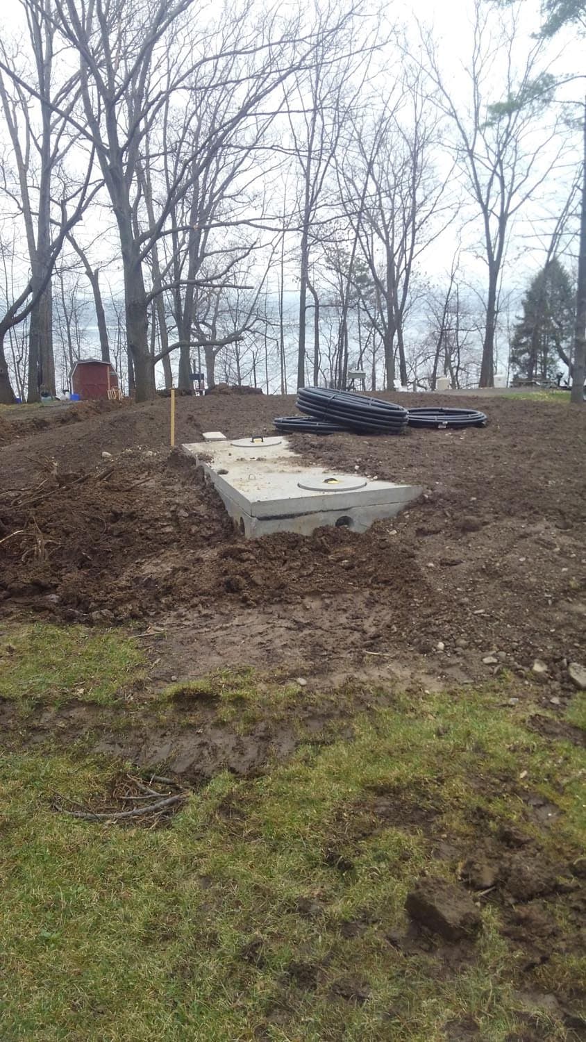 Concrete septic tank sections installed at construction site with bare trees in background